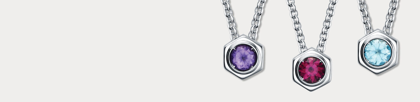 Birks Bee Chic Birthstones Rholodite, Amethyst, and Aquamarine and Silver Pendant on a beige background. 